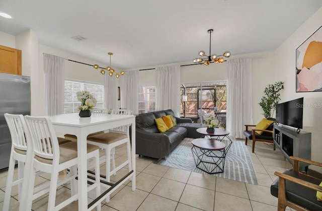 living room with a wealth of natural light, a chandelier, and light tile patterned flooring