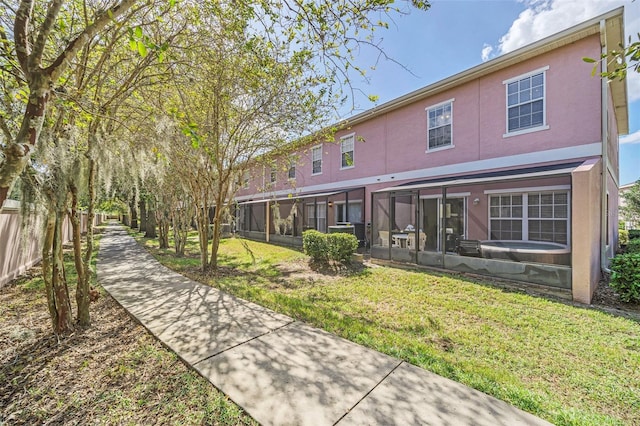 rear view of property featuring a sunroom and a yard