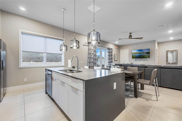 kitchen with ceiling fan, sink, pendant lighting, white cabinets, and an island with sink