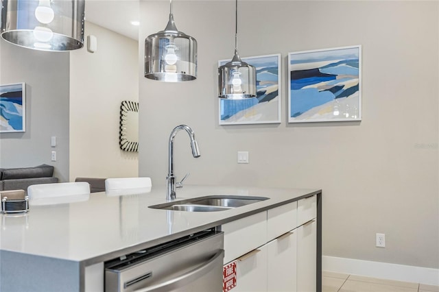 kitchen with stainless steel dishwasher, sink, light tile patterned floors, white cabinets, and hanging light fixtures