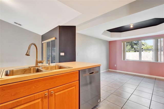 kitchen with a tray ceiling, stainless steel dishwasher, sink, and light tile patterned floors