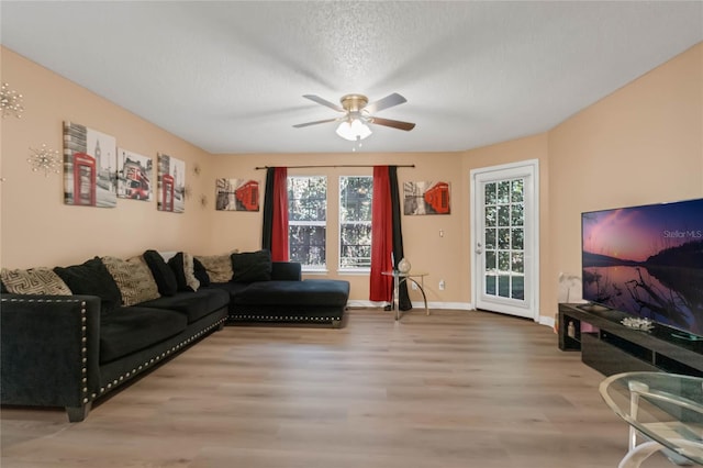 living room featuring a textured ceiling, ceiling fan, wood-type flooring, and plenty of natural light