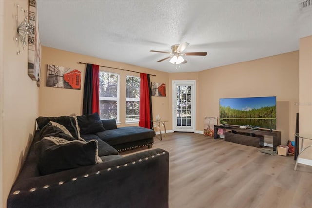 living room featuring ceiling fan, a textured ceiling, and hardwood / wood-style floors