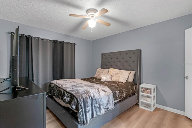 bedroom with light hardwood / wood-style floors, a textured ceiling, and ceiling fan