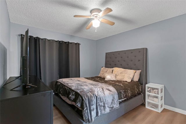 bedroom with a textured ceiling, wood-type flooring, and ceiling fan