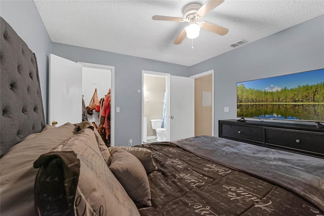 bedroom with a spacious closet, ensuite bath, a textured ceiling, a closet, and ceiling fan