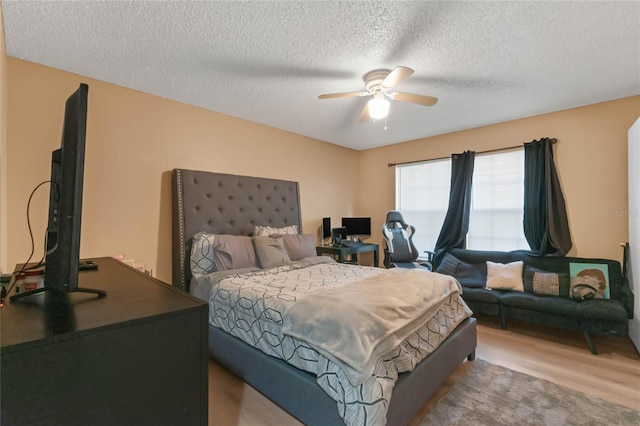 bedroom with light hardwood / wood-style flooring, a textured ceiling, and ceiling fan