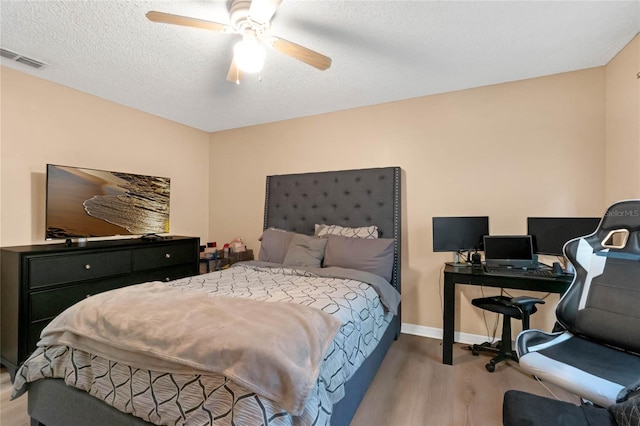 bedroom featuring light hardwood / wood-style floors, a textured ceiling, and ceiling fan