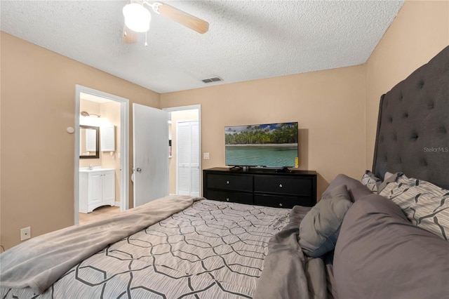 bedroom featuring a textured ceiling, ensuite bathroom, and ceiling fan