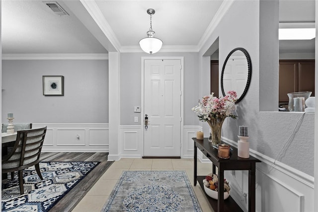 foyer entrance with ornamental molding and light hardwood / wood-style flooring