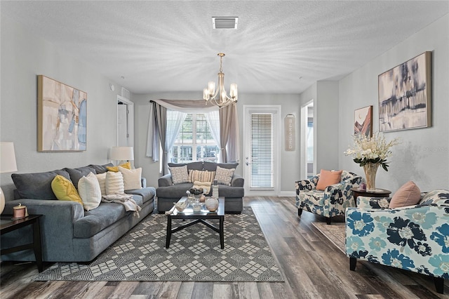 living room with an inviting chandelier, a textured ceiling, and dark wood-type flooring