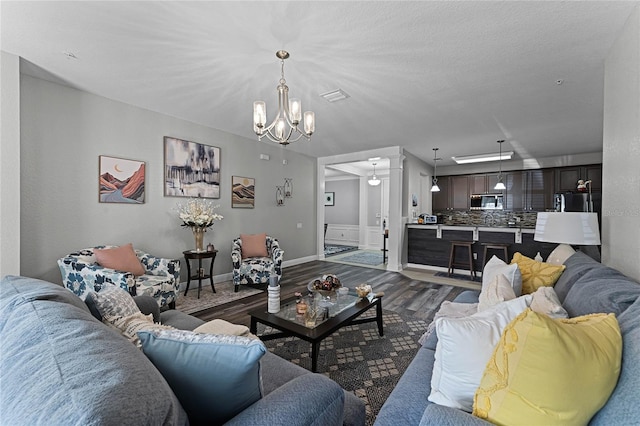 living room with dark wood-type flooring and a notable chandelier