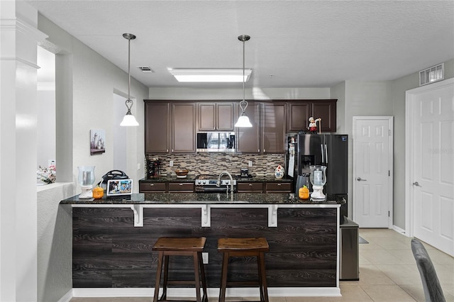 3356 Robert Trent Jones Dr Unit 101, Orlando, FL 32835 - kitchen with appliances with stainless steel finishes, a breakfast bar area, dark brown cabinetry, tasteful backsplash, and dark stone counters
