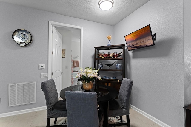 3356 Robert Trent Jones Dr Unit 101, Orlando, FL 32835 - dining area featuring light tile patterned floors, a textured ceiling, and baseboards