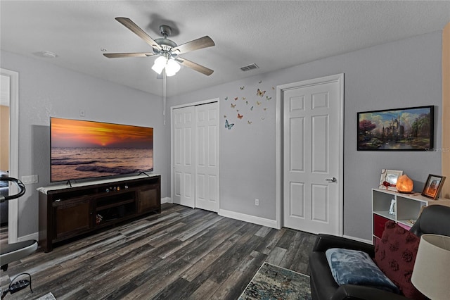 living room featuring ceiling fan, a textured ceiling, and dark hardwood / wood-style floors