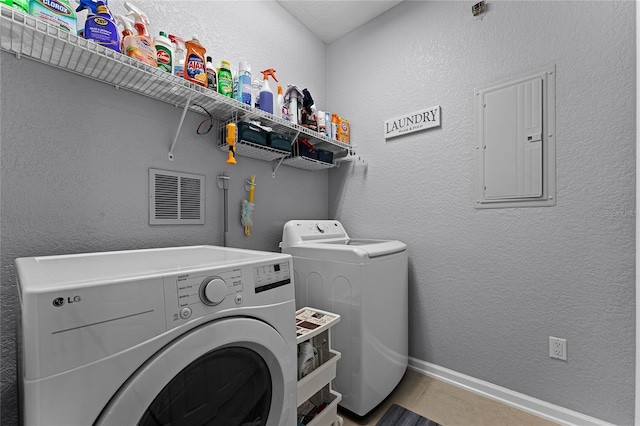 clothes washing area with electric panel, washer and dryer, and tile patterned flooring