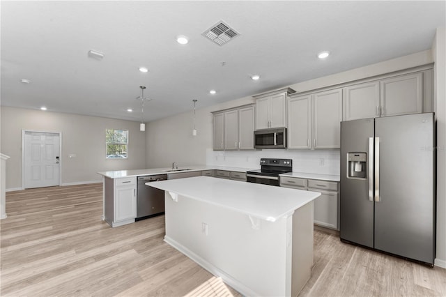 kitchen featuring stainless steel appliances, gray cabinets, sink, kitchen peninsula, and light hardwood / wood-style flooring