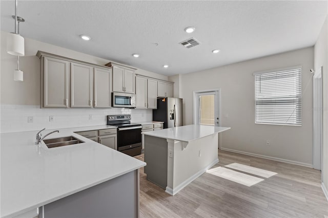 kitchen featuring sink, a breakfast bar area, a kitchen island, pendant lighting, and appliances with stainless steel finishes