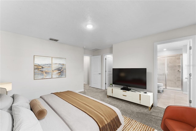 carpeted bedroom featuring ensuite bath and a textured ceiling