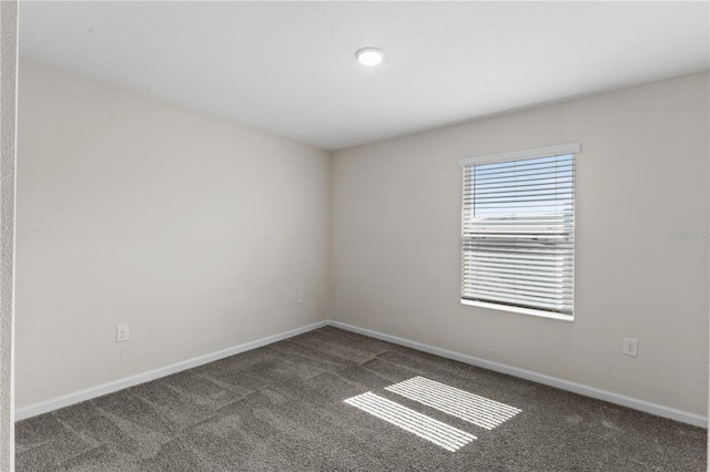 spare room featuring dark colored carpet