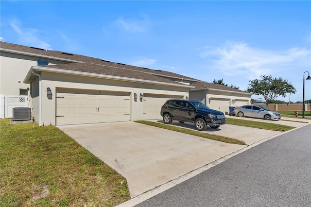 view of side of property featuring a garage, central AC, and a yard