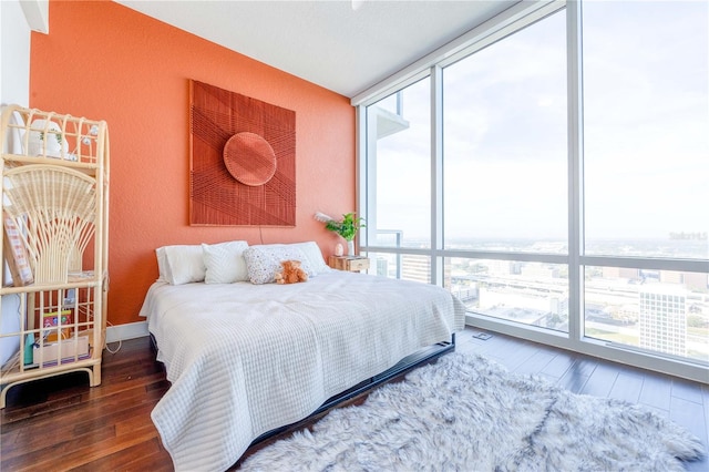 bedroom with dark hardwood / wood-style floors and a wall of windows