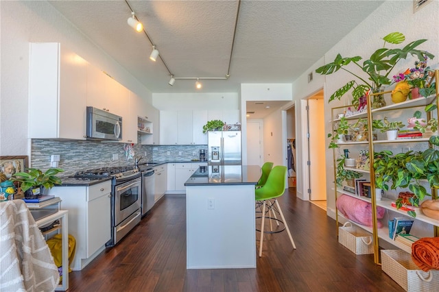 kitchen featuring white cabinetry, a center island, stainless steel appliances, dark hardwood / wood-style floors, and a textured ceiling