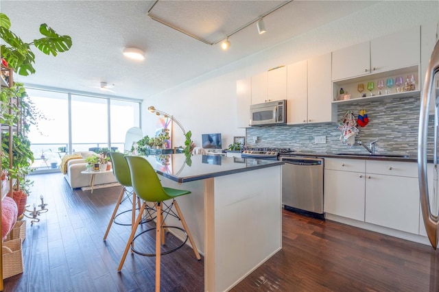 kitchen featuring white cabinetry, decorative backsplash, appliances with stainless steel finishes, dark hardwood / wood-style flooring, and a textured ceiling