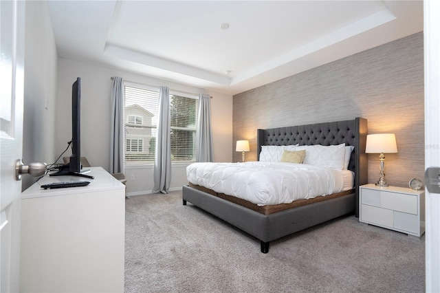 bedroom with light colored carpet and a raised ceiling