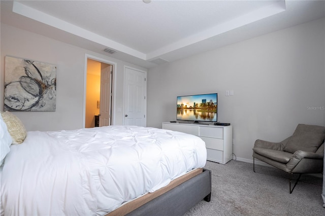 bedroom featuring light colored carpet and a tray ceiling