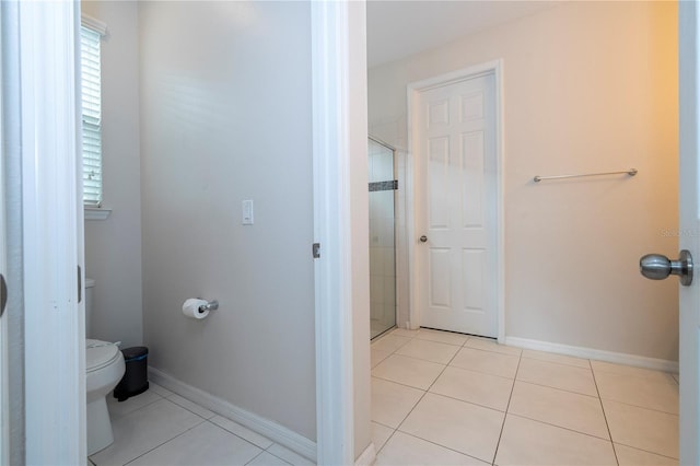 bathroom featuring toilet, tile patterned floors, and a shower with door