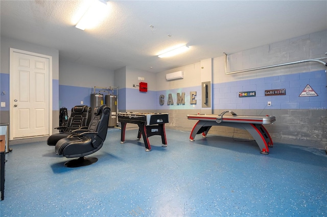 recreation room featuring electric panel, a wall unit AC, a textured ceiling, and electric water heater