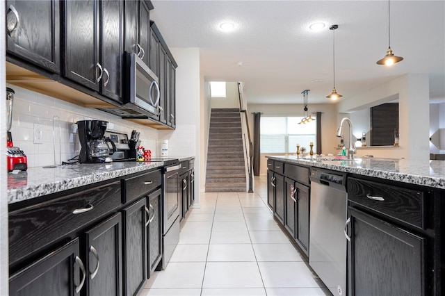 kitchen featuring decorative backsplash, hanging light fixtures, light tile patterned floors, light stone countertops, and appliances with stainless steel finishes