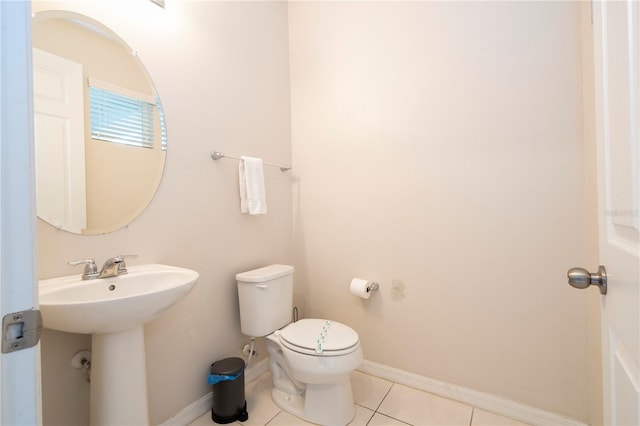 bathroom with toilet, sink, and tile patterned floors