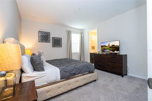 bedroom featuring ensuite bath and light carpet