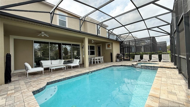 view of pool with an in ground hot tub, glass enclosure, a patio, ceiling fan, and an outdoor hangout area