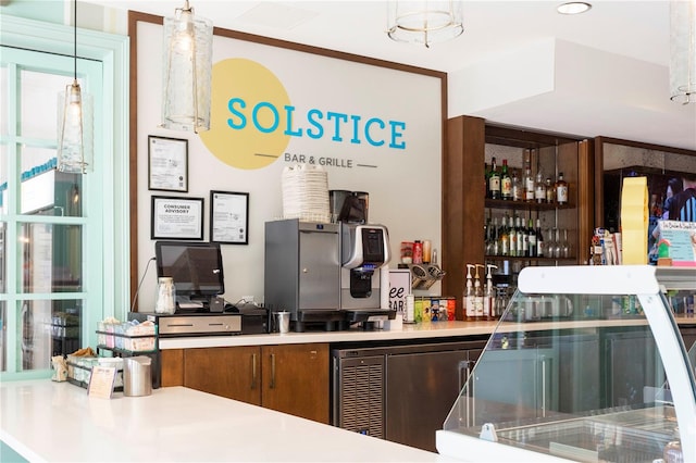 bar featuring decorative light fixtures, stainless steel fridge, and crown molding