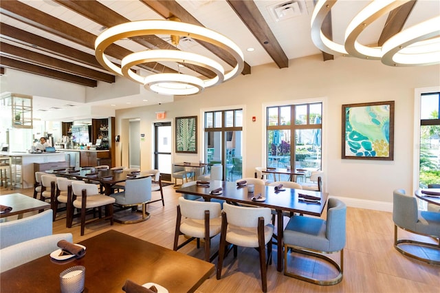 dining space with light wood-type flooring, a healthy amount of sunlight, and an inviting chandelier