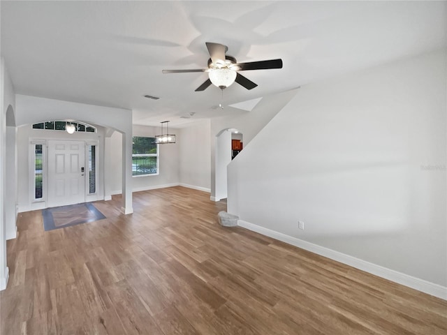 interior space with ceiling fan with notable chandelier and hardwood / wood-style floors