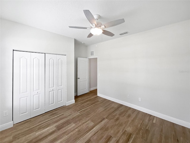 unfurnished bedroom with a closet, wood-type flooring, and ceiling fan