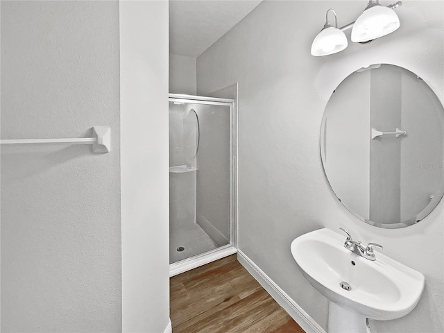 bathroom with a shower with door, sink, and wood-type flooring