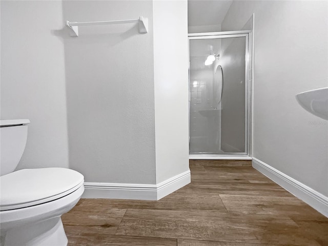 bathroom featuring toilet, hardwood / wood-style flooring, and a shower with shower door