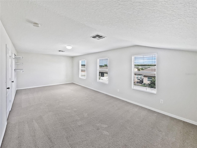 unfurnished room featuring a textured ceiling, vaulted ceiling, and carpet flooring