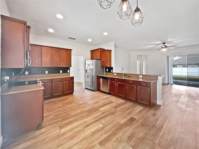 kitchen with sink, appliances with stainless steel finishes, decorative light fixtures, and light wood-type flooring