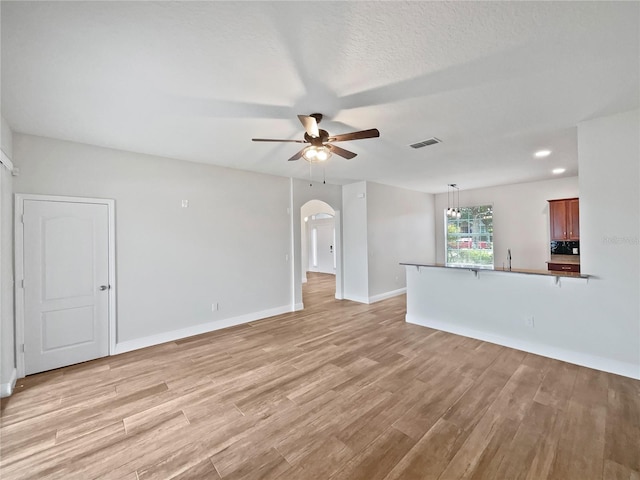 unfurnished living room featuring light hardwood / wood-style floors, a textured ceiling, and ceiling fan