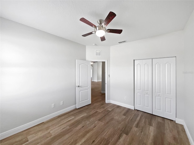 unfurnished bedroom with dark hardwood / wood-style floors, a closet, and ceiling fan