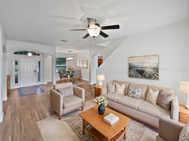 living room with ceiling fan with notable chandelier and light wood-type flooring