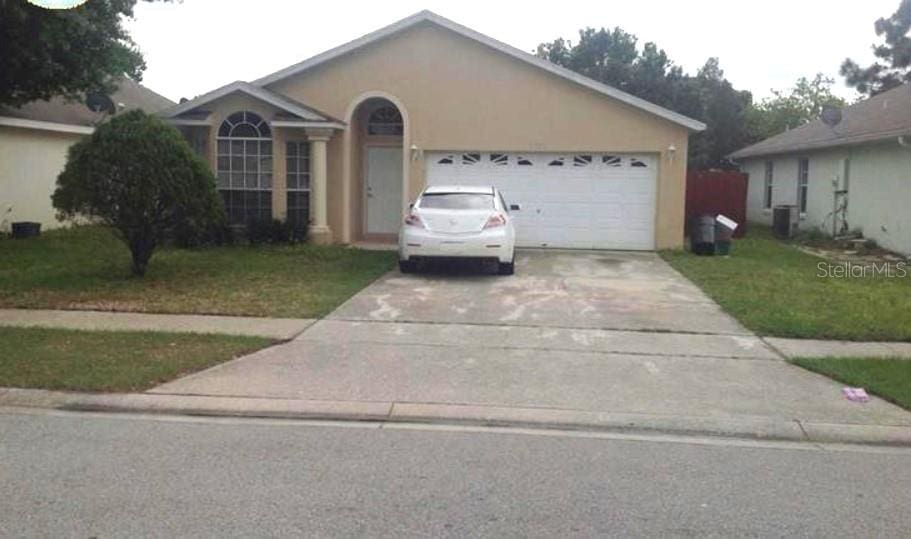 single story home with a front yard, a garage, and central air condition unit