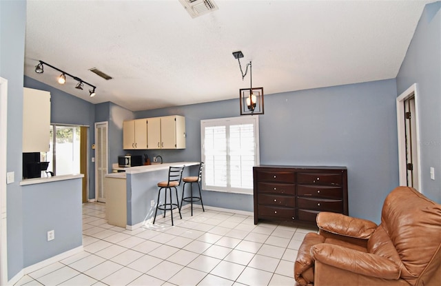 kitchen featuring cream cabinets, light tile patterned flooring, plenty of natural light, and hanging light fixtures