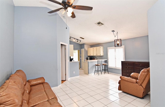 living room with vaulted ceiling, ceiling fan, rail lighting, and light tile patterned floors